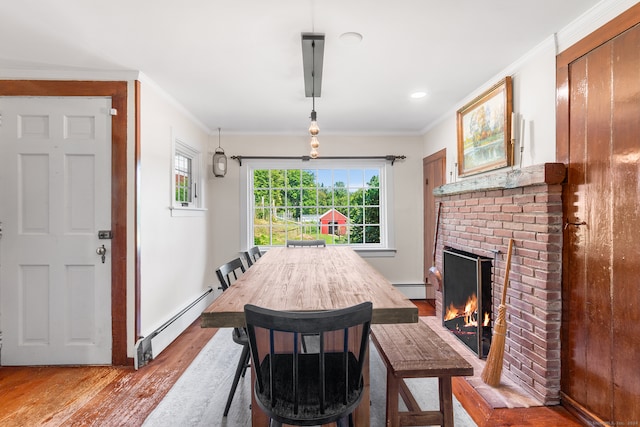 dining room with ornamental molding, a brick fireplace, light hardwood / wood-style floors, and baseboard heating