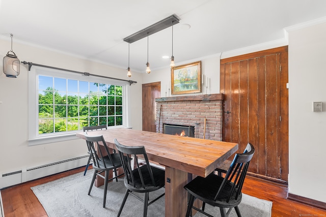 dining space featuring crown molding, a fireplace, a baseboard heating unit, and dark wood-type flooring