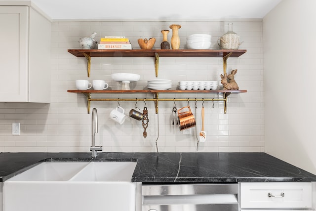 kitchen featuring dark stone counters, tasteful backsplash, sink, white cabinetry, and stainless steel dishwasher