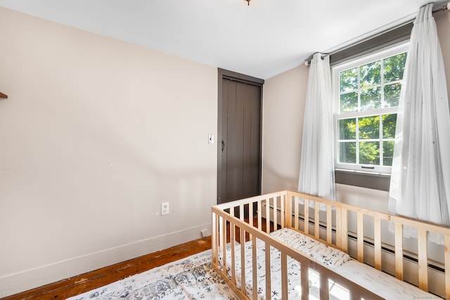 bedroom featuring a baseboard radiator, a nursery area, and light hardwood / wood-style flooring