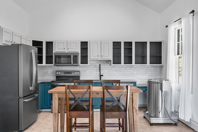 kitchen featuring appliances with stainless steel finishes, a healthy amount of sunlight, blue cabinets, and white cabinets