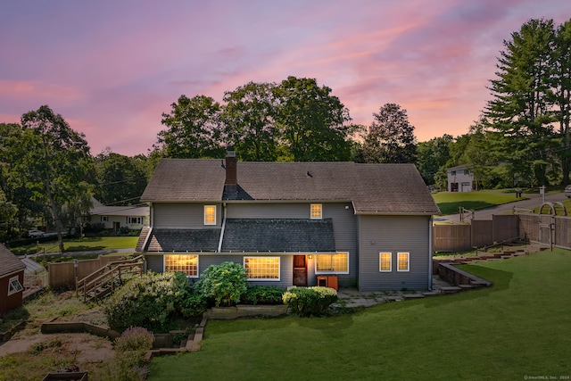 back house at dusk with a lawn