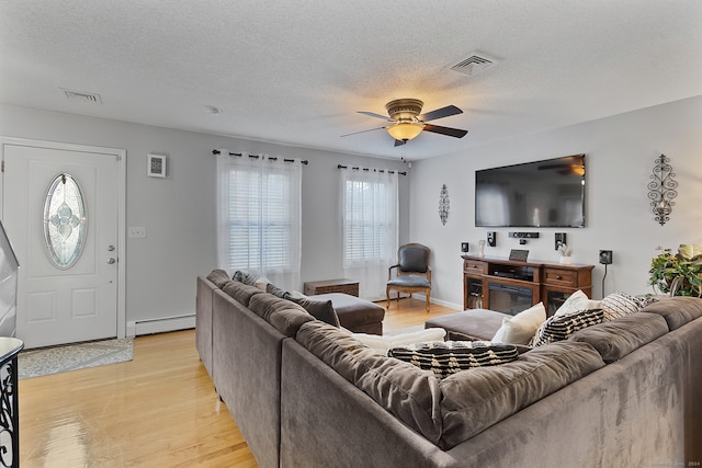 living room featuring ceiling fan, a textured ceiling, baseboard heating, and light hardwood / wood-style floors