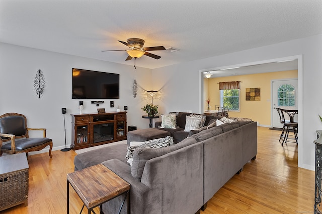 living room featuring light wood-type flooring, a textured ceiling, and ceiling fan