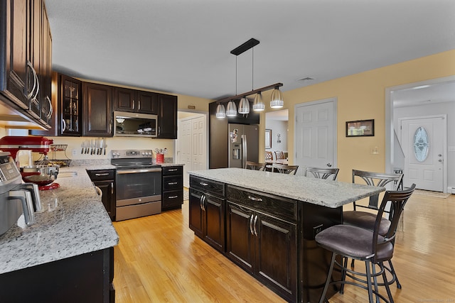 kitchen with a kitchen breakfast bar, a kitchen island, light hardwood / wood-style flooring, and stainless steel appliances