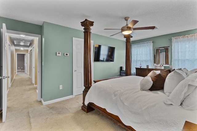 bedroom with ceiling fan, a textured ceiling, and light carpet