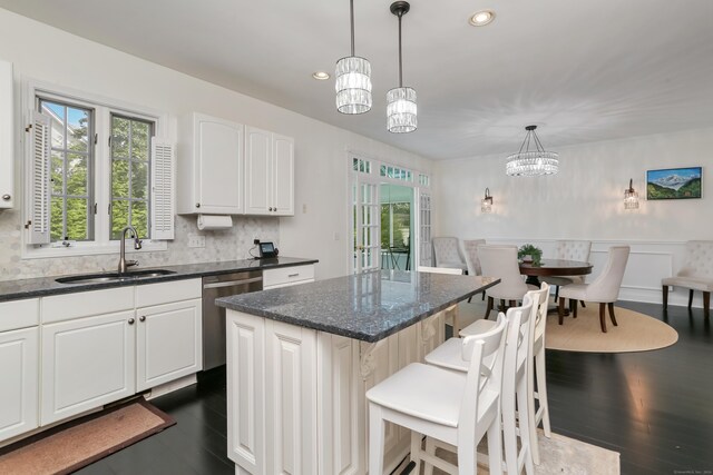 kitchen with pendant lighting, a notable chandelier, dishwasher, sink, and a center island