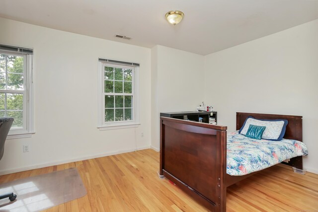 bedroom with multiple windows and light hardwood / wood-style floors