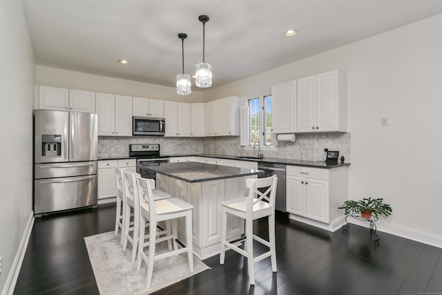 kitchen with white cabinets, pendant lighting, a kitchen island, and stainless steel appliances