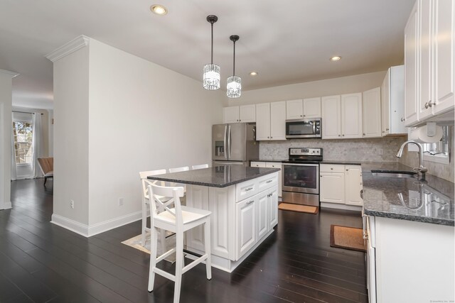 kitchen with decorative light fixtures, dark hardwood / wood-style flooring, a center island, appliances with stainless steel finishes, and white cabinets