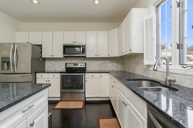 kitchen featuring sink, appliances with stainless steel finishes, dark stone counters, and white cabinets