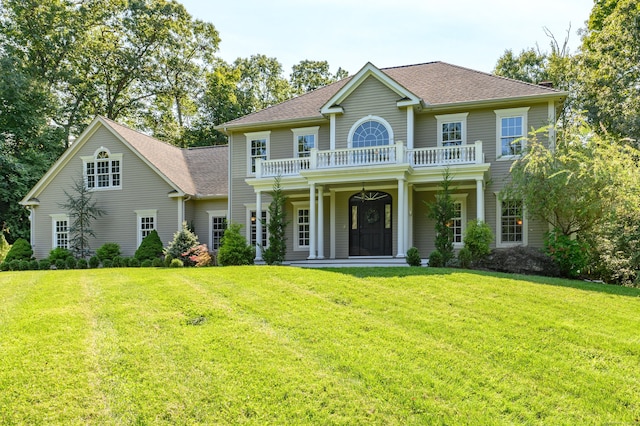 colonial inspired home with a balcony, a porch, and a front lawn