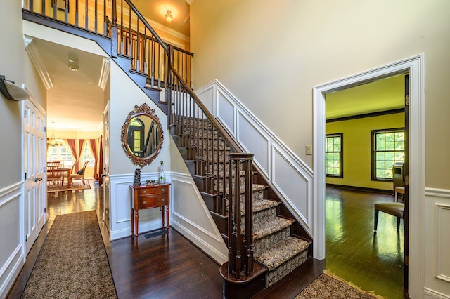 staircase with wood-type flooring and ornamental molding