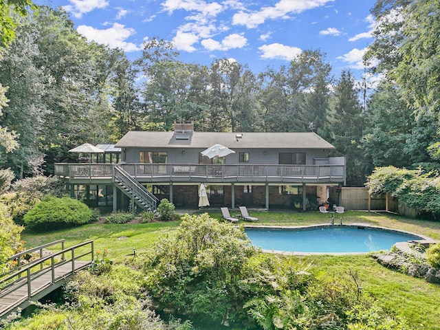 rear view of house featuring a pool side deck and a lawn