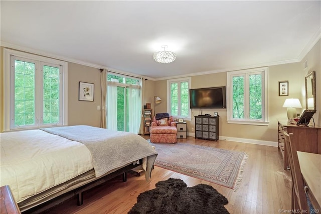 bedroom featuring crown molding, light hardwood / wood-style flooring, and multiple windows