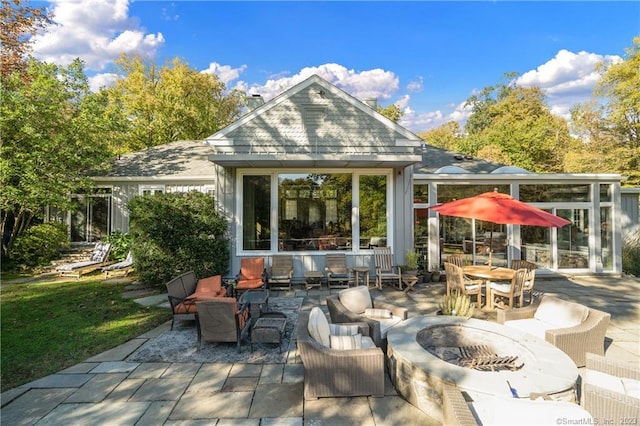 rear view of property featuring a patio area and an outdoor living space with a fire pit