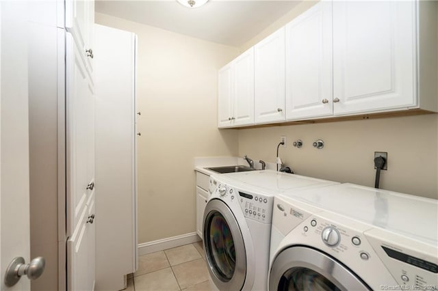 clothes washing area featuring cabinets, light tile patterned floors, washing machine and dryer, and sink