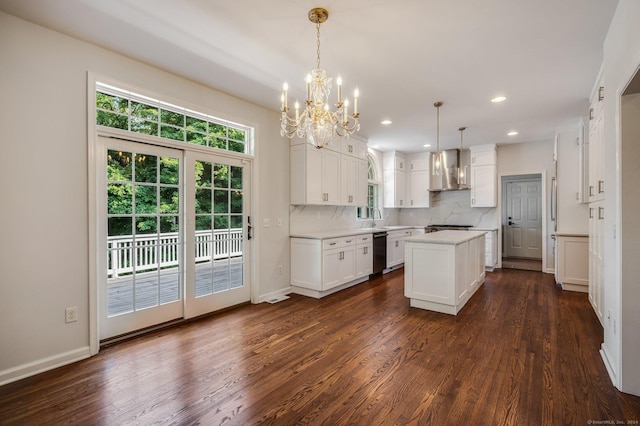 kitchen with decorative light fixtures, white cabinetry, black dishwasher, a center island, and wall chimney range hood