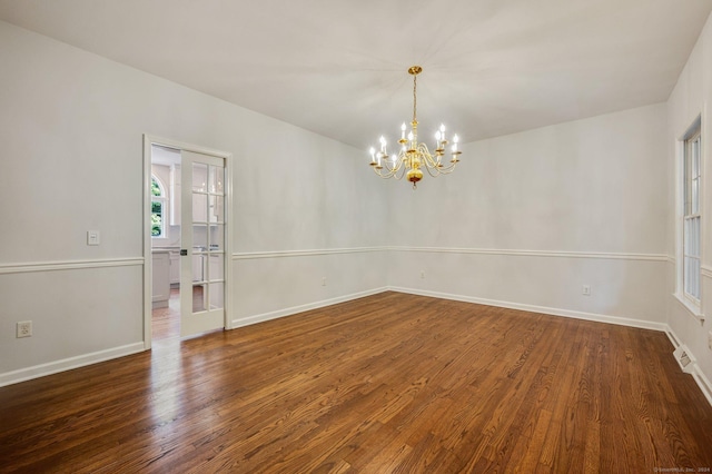 empty room featuring dark hardwood / wood-style floors and an inviting chandelier