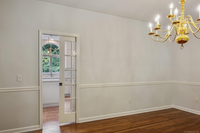 unfurnished room featuring dark wood-type flooring and an inviting chandelier