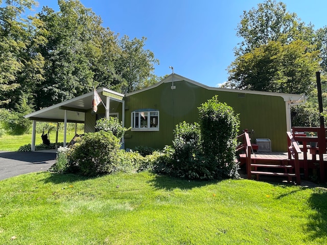 view of home's exterior featuring a lawn, a wooden deck, and a carport