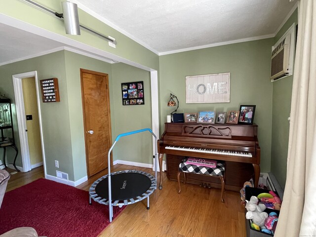 miscellaneous room featuring a textured ceiling, crown molding, an AC wall unit, and hardwood / wood-style floors