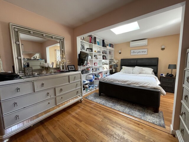 bedroom with wood-type flooring and an AC wall unit