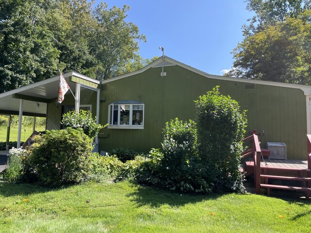 view of home's exterior with a wooden deck and a yard