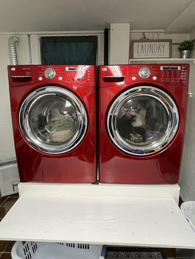 clothes washing area with separate washer and dryer and dark tile patterned floors