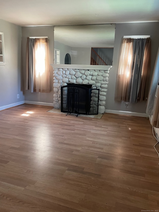 unfurnished living room with dark wood-type flooring and a stone fireplace