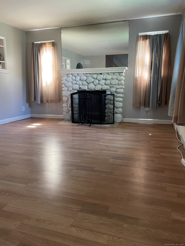 unfurnished living room featuring dark hardwood / wood-style floors and a stone fireplace