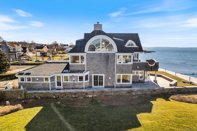 back of property featuring a water view, a patio area, and a lawn