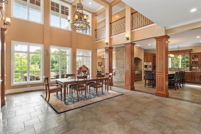 162 Balfour Dr, West Hartford, CT 06117 - dining area featuring decorative columns, crown molding, stone tile floors, a towering ceiling, and a chandelier
