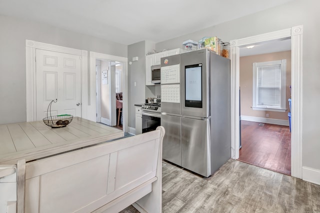 kitchen with light wood-type flooring, tile countertops, stainless steel appliances, and white cabinets