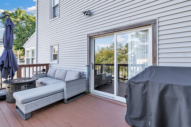 wooden terrace with an outdoor living space with a fire pit and grilling area