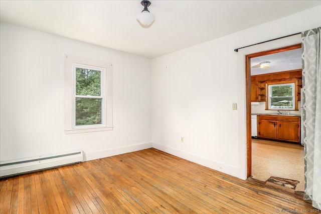 empty room with light hardwood / wood-style floors and a baseboard heating unit