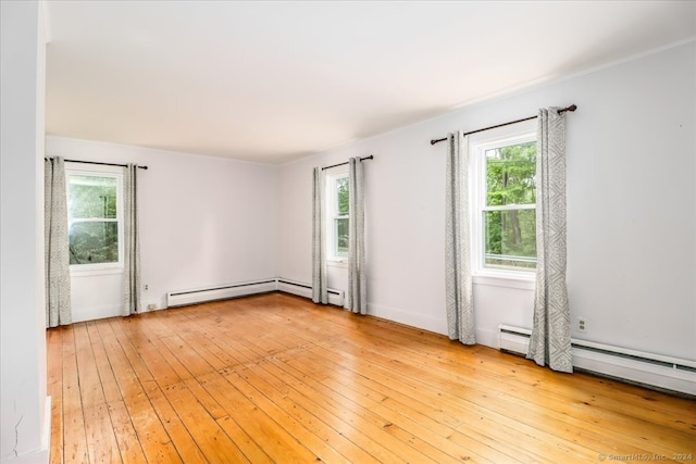 empty room with baseboard heating and light wood-type flooring