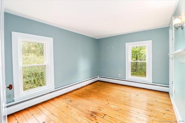 spare room with a healthy amount of sunlight, a baseboard radiator, and light wood-type flooring