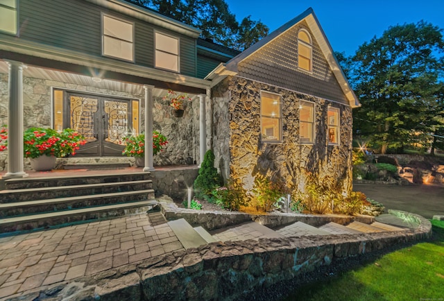 back of property with french doors, covered porch, and stone siding