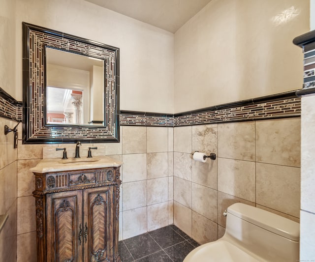 bathroom featuring tile walls, vanity, and toilet