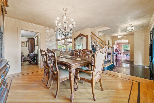 dining area with ornamental molding, wood finished floors, stairway, a chandelier, and arched walkways