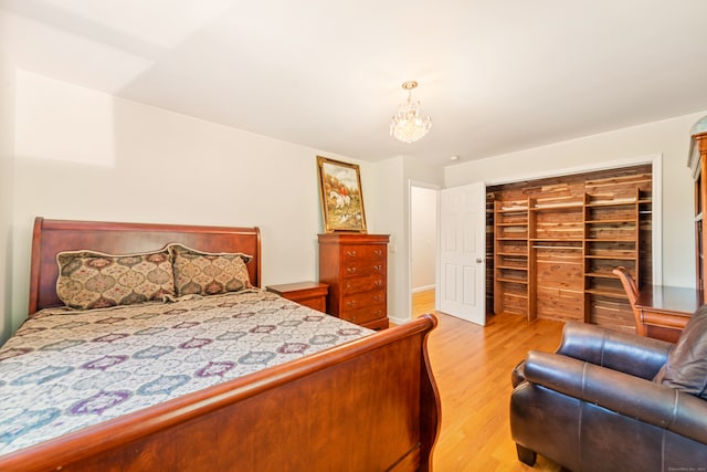 bedroom with a spacious closet, light hardwood / wood-style flooring, a closet, and a notable chandelier