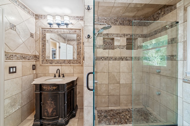 bathroom featuring walk in shower, vanity, and tile walls