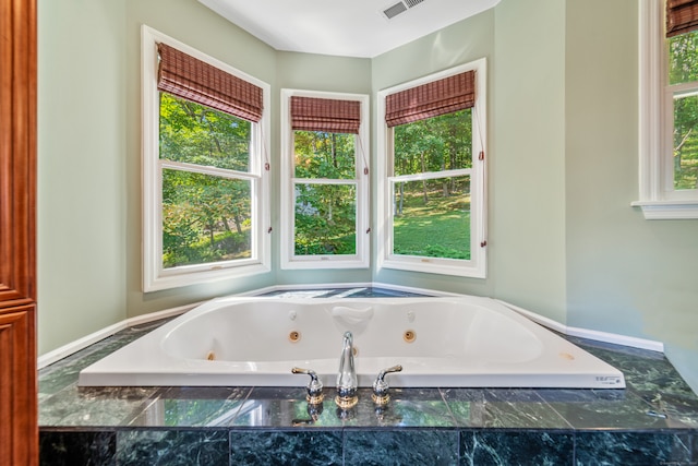 bathroom featuring a healthy amount of sunlight and tiled tub