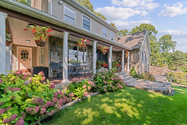 exterior space with a lawn, covered porch, and stone siding