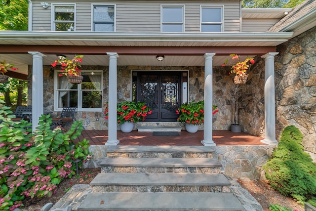 view of exterior entry with a porch, french doors, and stone siding