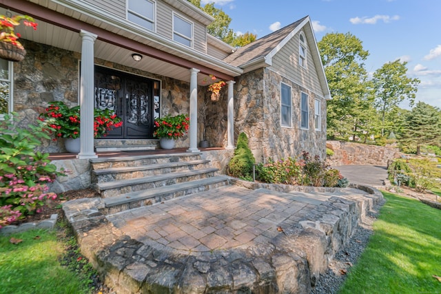 property entrance featuring covered porch and stone siding