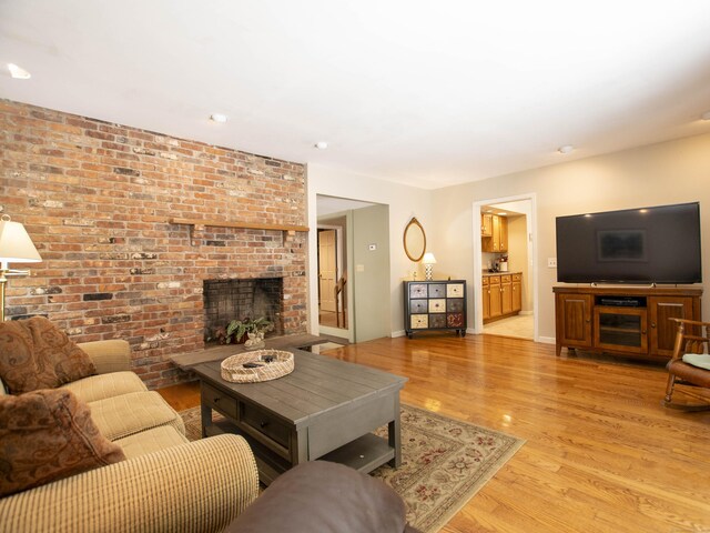 living room with a brick fireplace and light wood-type flooring