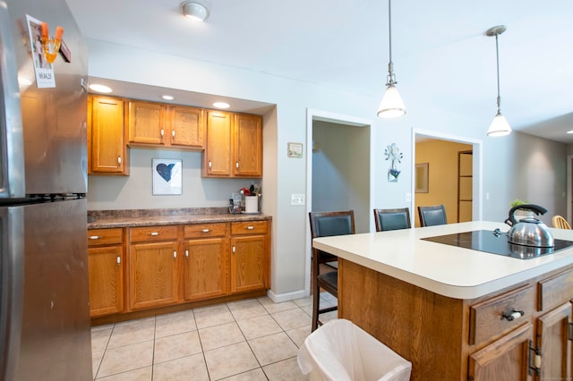 kitchen featuring pendant lighting, light tile patterned flooring, a breakfast bar, stainless steel refrigerator, and a center island