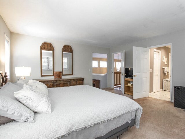 bedroom featuring ensuite bath and light colored carpet